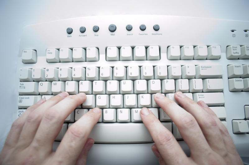 hands typing at a computer keyboard with a cross procesed colours