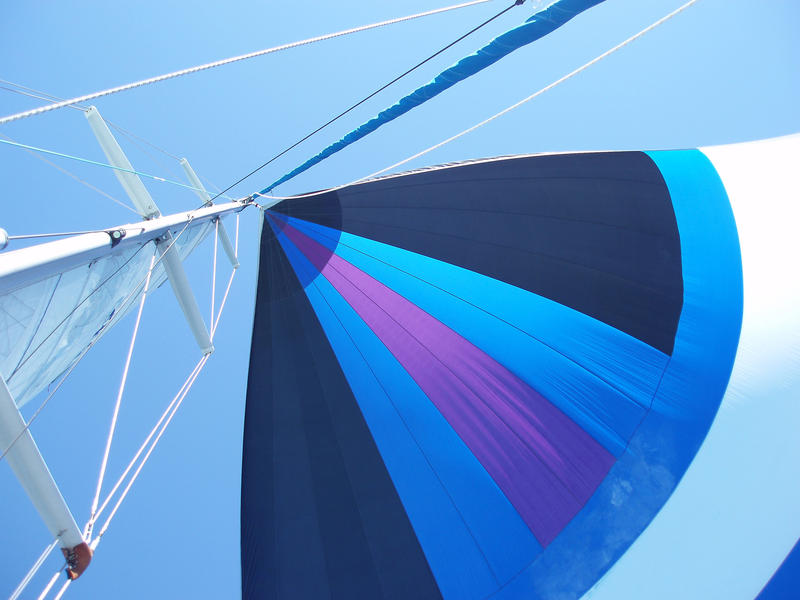 looking up from the bottom of a yacht mast at a sail and rigging