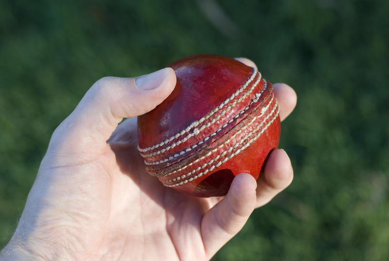 a hand holding a cricket ball ready for bowling
