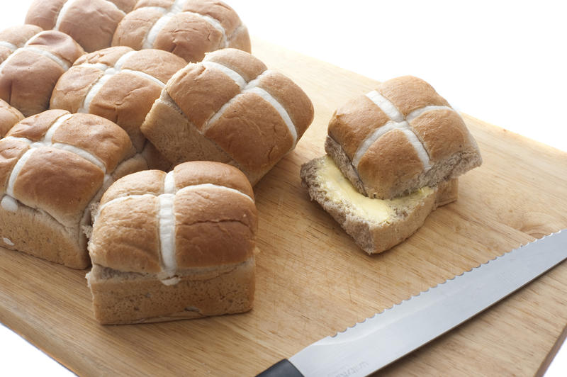 Buttered Fresh Hot Cross Buns on a wooden board to celebrate Easter