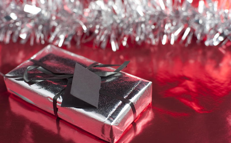 a christmas present wrapped in metallic foil wrapping paper and ribbon