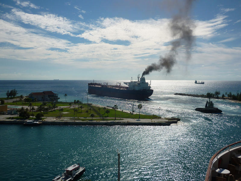 a container ship leaving post with a large plume of smoke