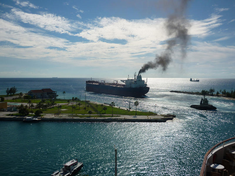 a container ship leaving post with a large plume of smoke