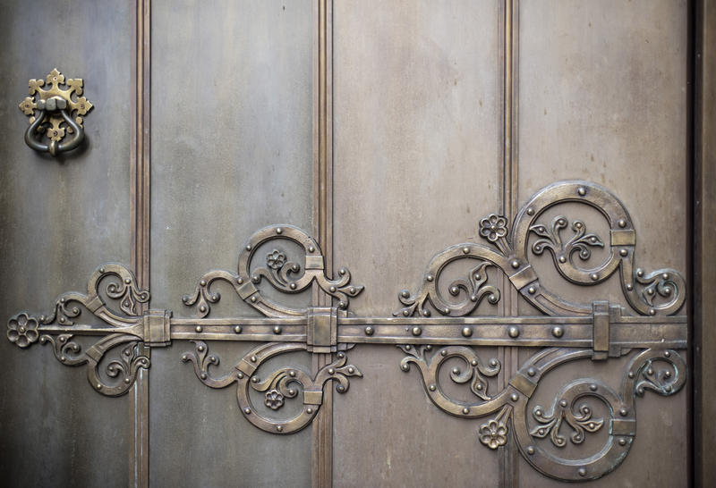 an ornate metal door with large decorative hinge motif