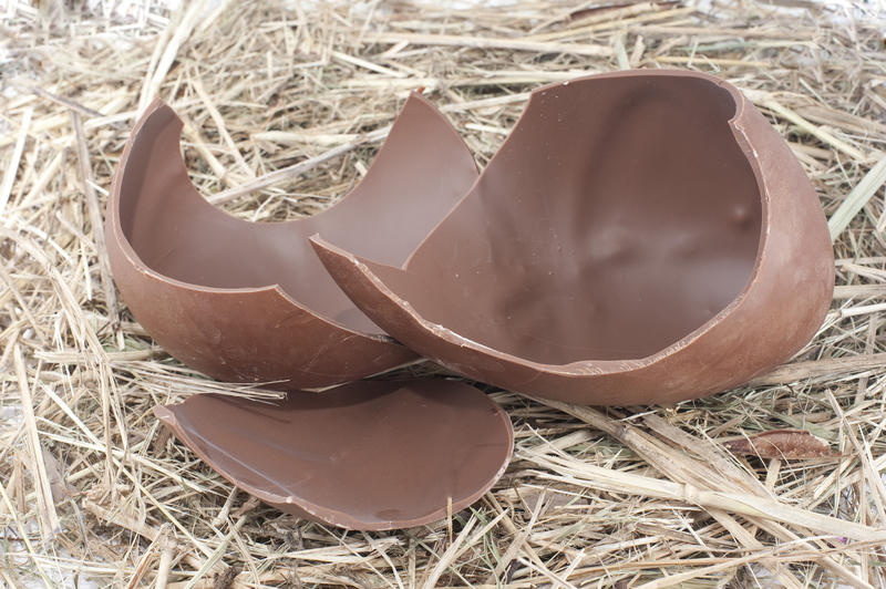 Chocolate Easter Egg broken into pieces on a background of fresh straw