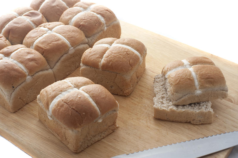 Traditional fresh Easter Hot Cross Buns with frosted cross decoration on a wooden board