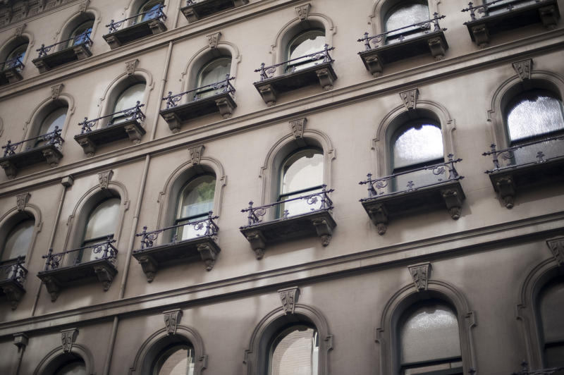 an ornate concrete facade, windows with cast iron railings