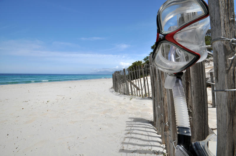 A snorkel & mask hang on a fence at Plage Saleccia  