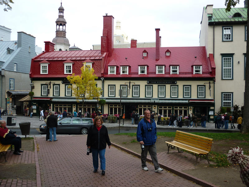 Historical external facade of a restaurant in Quebec City, Canada with people approaching the camera down a walkway