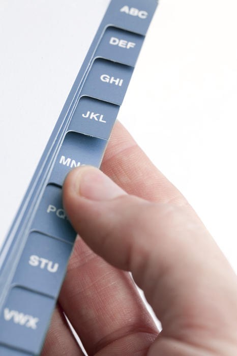 Male fingers looking up an address in an alphabetically tabbed address book