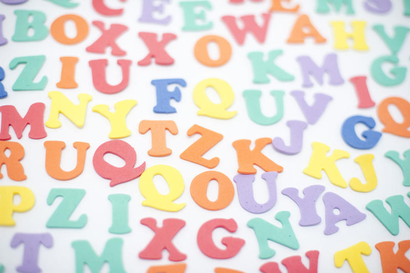 Colourful alphabet background with random scattered uppercase letters on a white surface