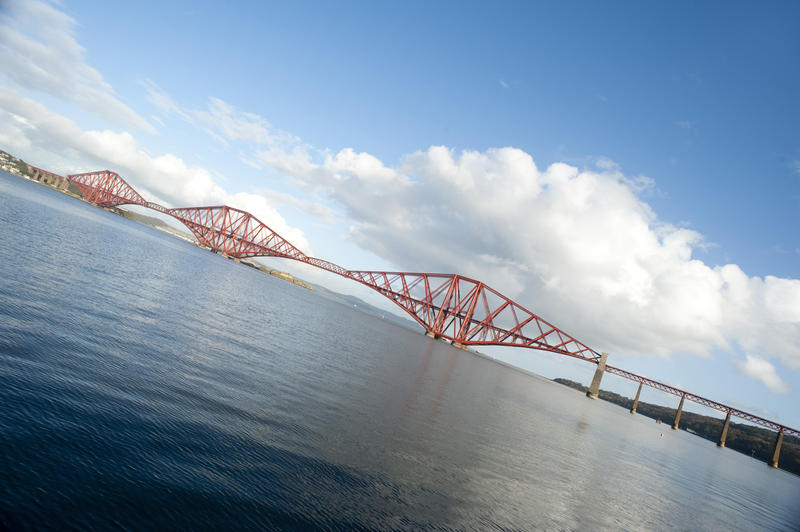 angled view of the forth bridge and the firth of forth on a sunny day with light clouds
