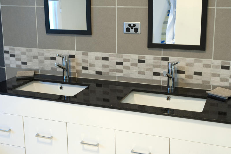Dual bathroom marble topped vanity with two sinks or handbasins in a modern tiled bathroom interior