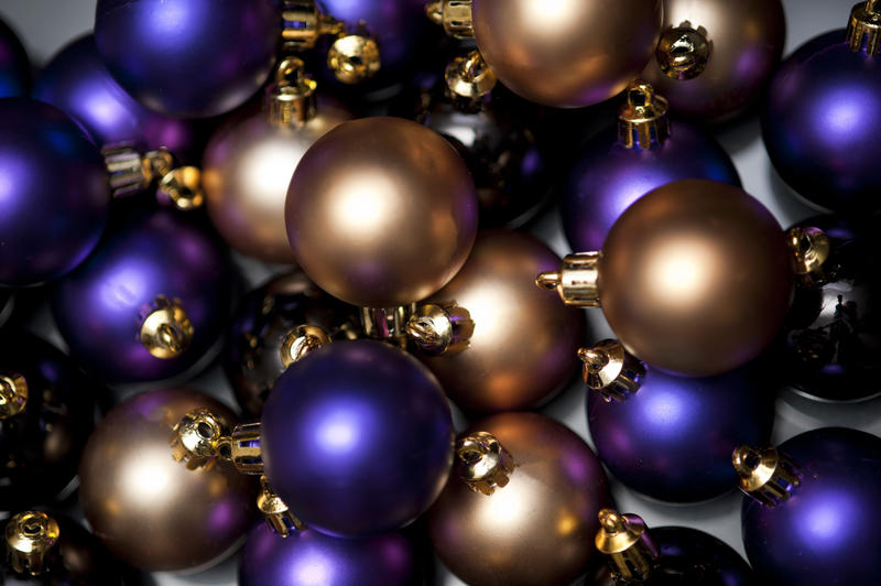 Glowing Christmas bauble background with a scattered array of colourful purple and gold balls