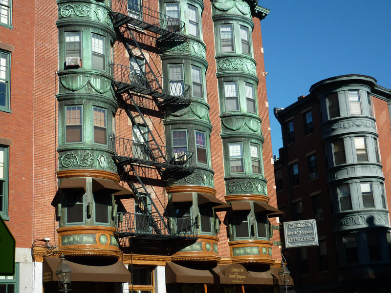 The facade of a building in Boston, showing ornate bay windows and ironwork exterior fire escapes