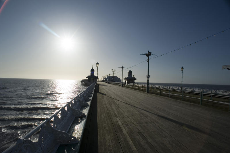 View along the deserted wooden broadwalk on Blackpool North Pier facing into the setting evening sun