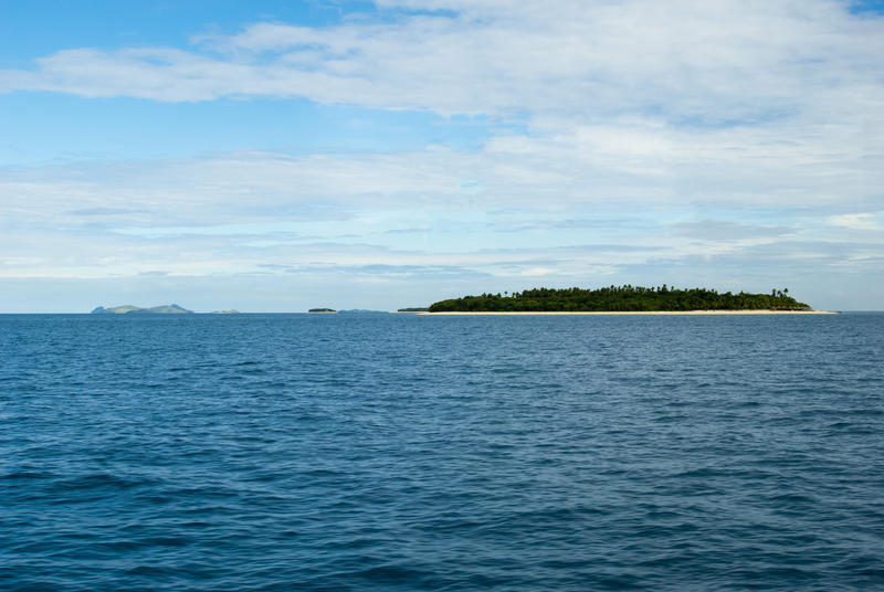 View across calm open ocean to low lying Bounty island, Fiji, a popular tourist destination