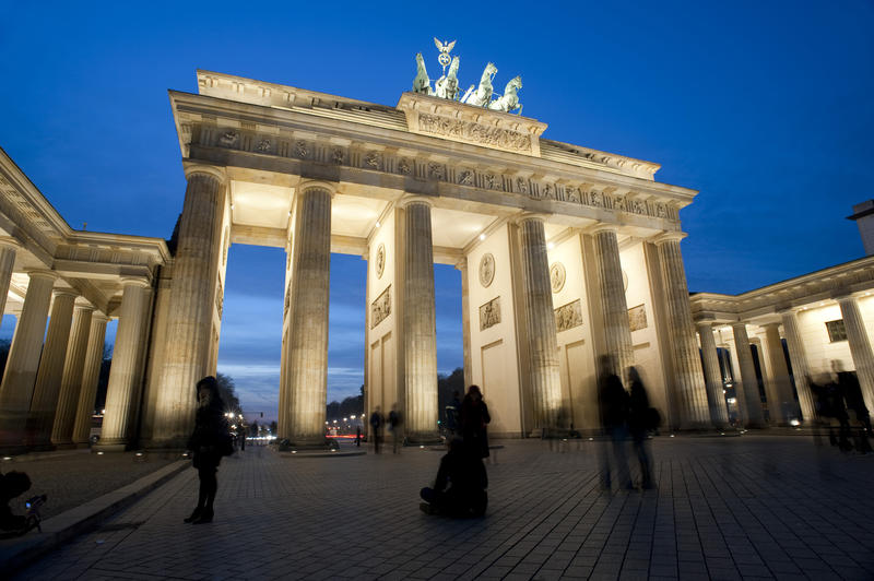 Night view of the Brandenberger gate, Berlin, Germany lit by floodlights with the silhouettes of pedestrians in the foreground
