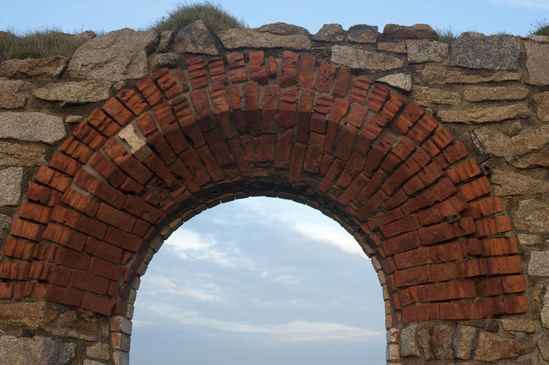 Historic Cornish tin mine ruins with an old brick and stone archway at the Levant tin mine, Pendeen against a blue sky