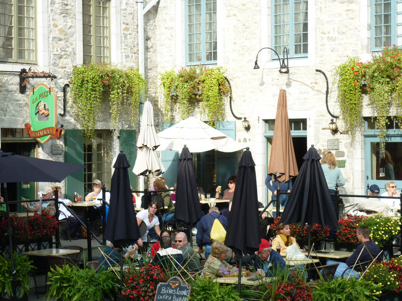 Conceptual of an outdoor cafe society with people seated at tables at an open-air restaurant enjoying refreshments in the sunshine