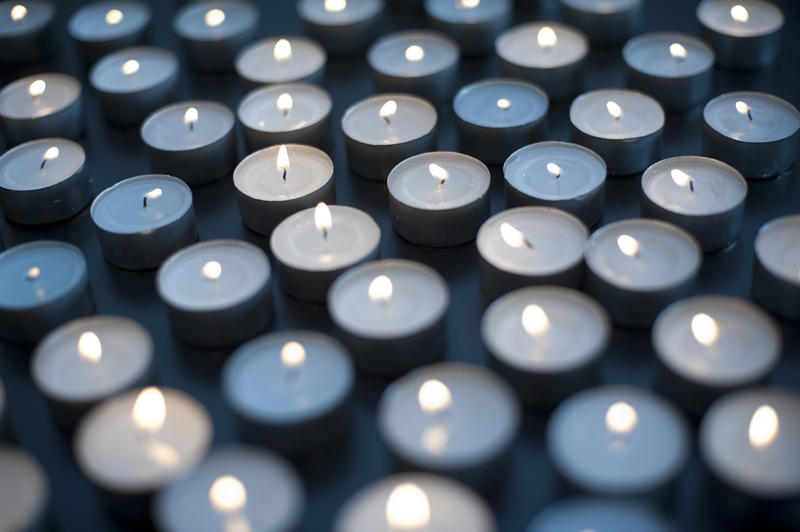 Burning candle backdrop with a myriad of small round candles close together celebrating a festivity or as a memorial or vigil to a loved one
