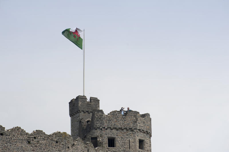 The national flag of Wales with its red dragon flying above the medieval ramparts of the keep at Cardiff Castle