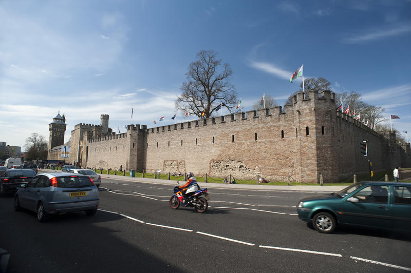 View from the street with traffic in the foreground of the perimeter walls of Cardiff Castle in Cardiff, Wales