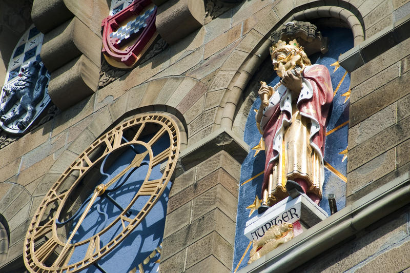 One of the gilded metal clock faces on the clock tower of Cardiff Castle, Wales flanked by sculptures representing the planets