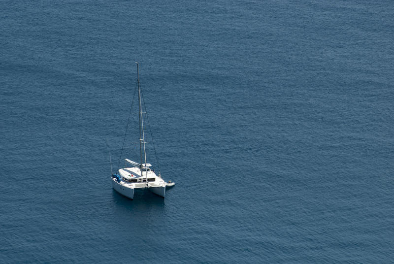 Luxury catamaran moored offshore with a dinghy alongside during a tropical summer vacation, in mid ocean with copyspace