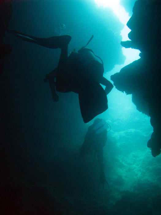 Scuba divers cave diving exploring the blue waters of the tropical sea off a Fijian island