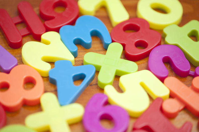 Multicolored plastic numbers spread out on wooden desk