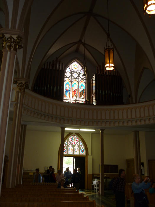 Church interior with congregation looking towards the arched entrance door and beautiful stained glass windows