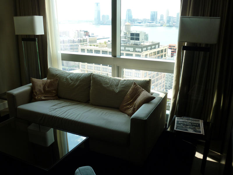 Interior of the small living room of a city apartment with a comfortable sofa in front of large glass windows with a view of the city