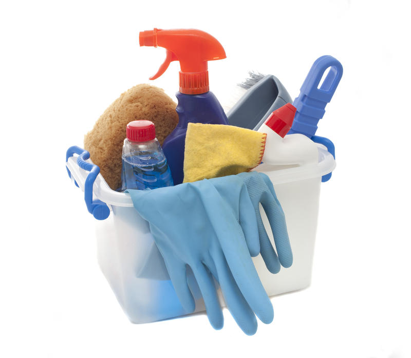 Plastic tub filled with household cleaning products including detergents, a spray bottle, gloves, sponge and cloth to ensure a healthy lifestyle
