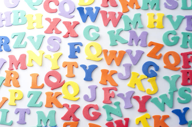 Colourful consonants background with uppercase alphabet letters scattered randomly over a white surface