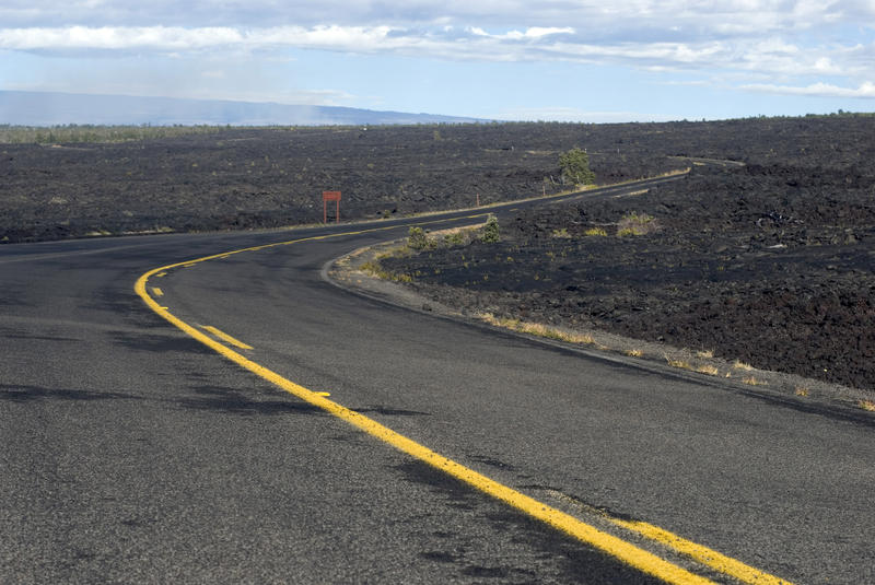 a road winds it's way around volcanic lava fields