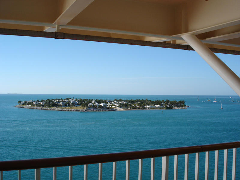 Cruising past an inhabited tropical island on an ocean liner with a view from the deck