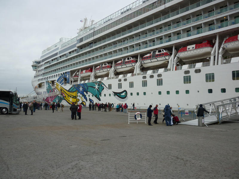 Large passenger liner or cruise ship in dock moored alongside the wharf with passengers coming and going using the gangplank