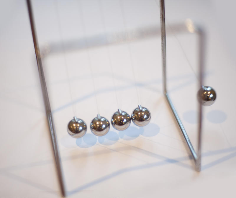 Newtons cradle desktop toy for the amusement of business executives who can watch the transfer of motion between the suspended metal balls