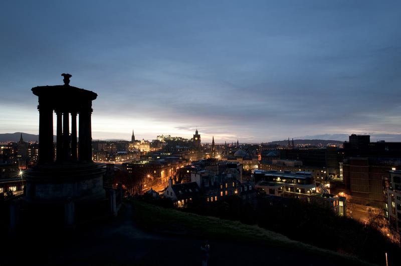 View of Edinburgh at night from Carlton Hill with the Dugald Stewart monument on the foreground and the floodlit castle on the horizon