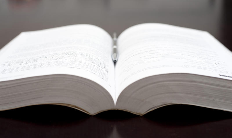 Studying concept closeup of an open textbook with a pen resting in the centre