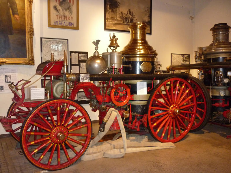 Historic restored red steam fire engine with metal spoked wheels on display in a museum