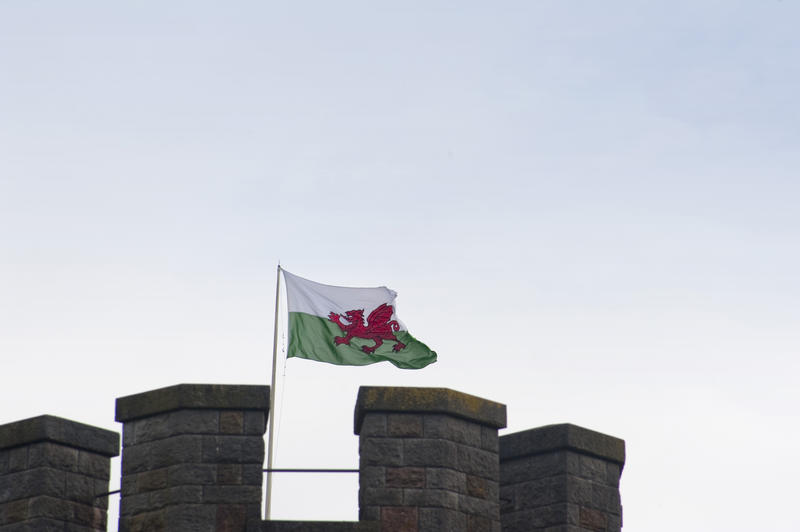 The Welsh Flag , otherwise called Baner Cymru or Y Ddraig Goch, meaning The Red Dragon, flying over the ramparts of a castle in Wales