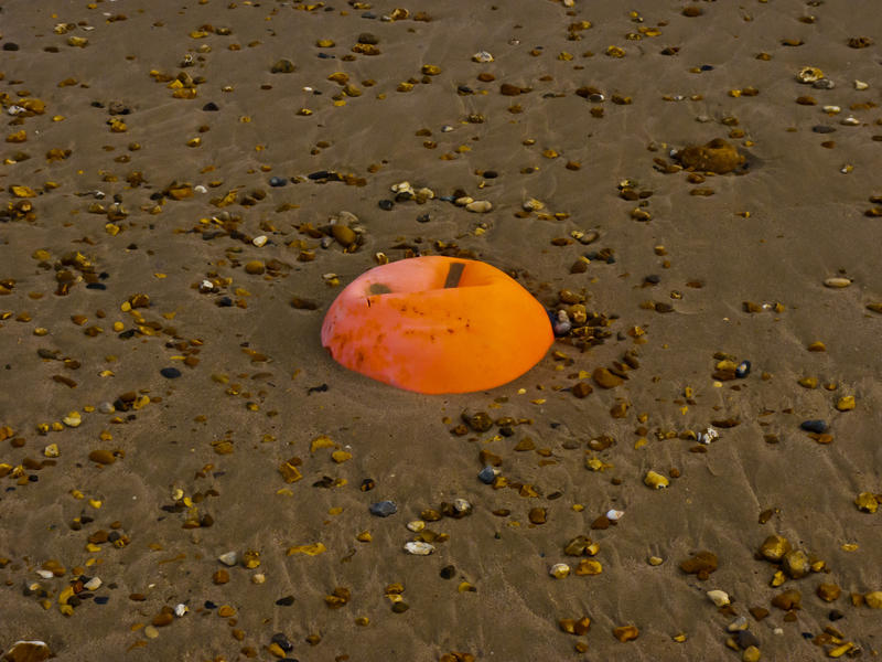 <p>Foreshore Bouy Trapped</p>The tide is out revealing the wet sand and stony foreshore and an old bouy trapped and slowly sinking.