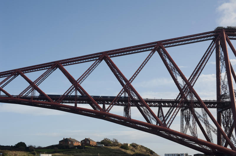 low angle view of a train crossing the forth bridge above the houses of north queensferry, scotland