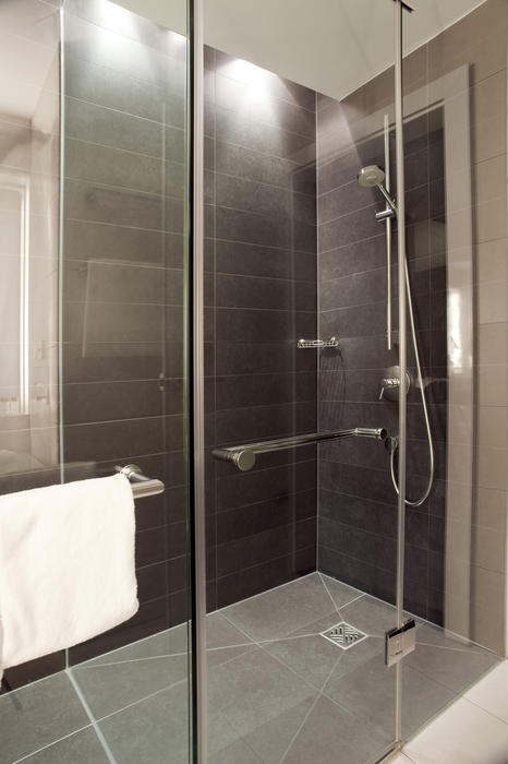 Large glass shower cubicle in a modern tiled bathroom interior with a clean white towel hanging on the glass door
