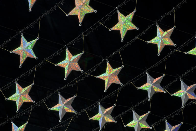 Seasonal background of an interlinked suspended Christmas star curtain with golden stars over a dark background