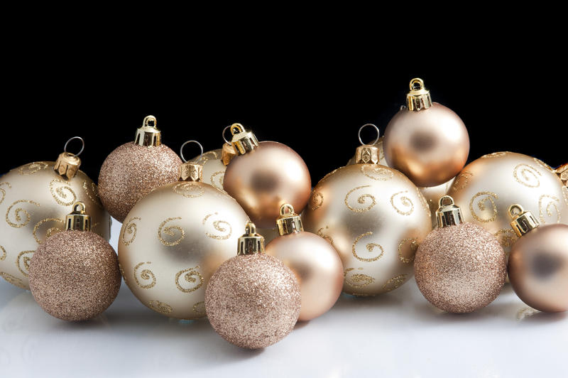 Collection of gold Christmas baubles of different sizes, some patterned, some decorated with glitter, with copyspace for your seasonal greeting