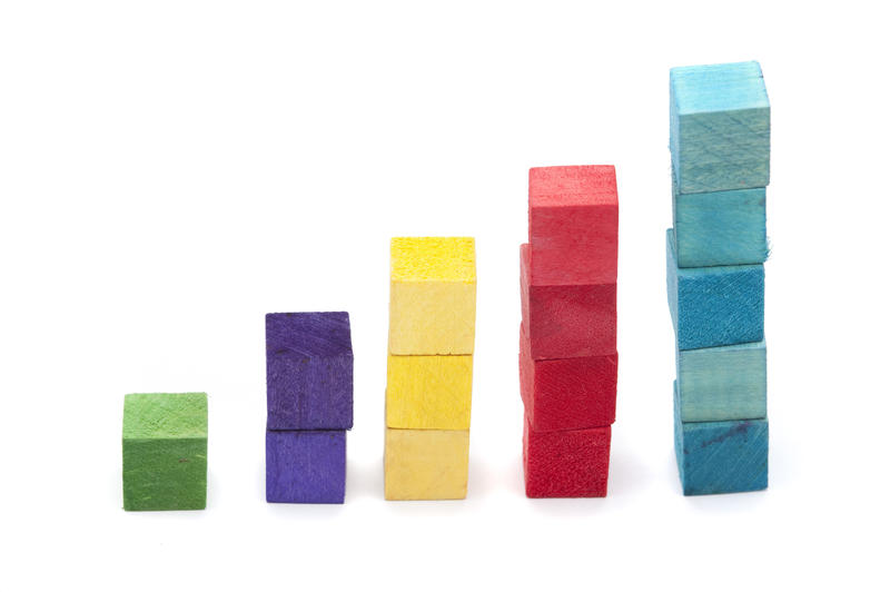 Growing concept represented by stacks of colourful wooden toy building blocks in increasing heights