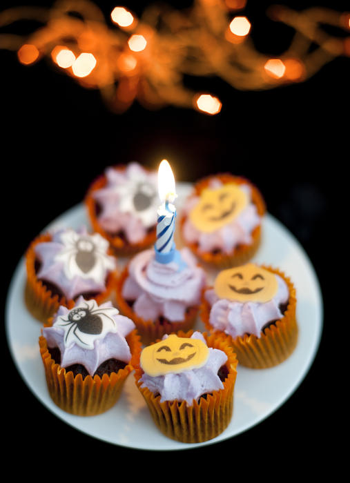 a plate of halloween treats with a candle on a black background